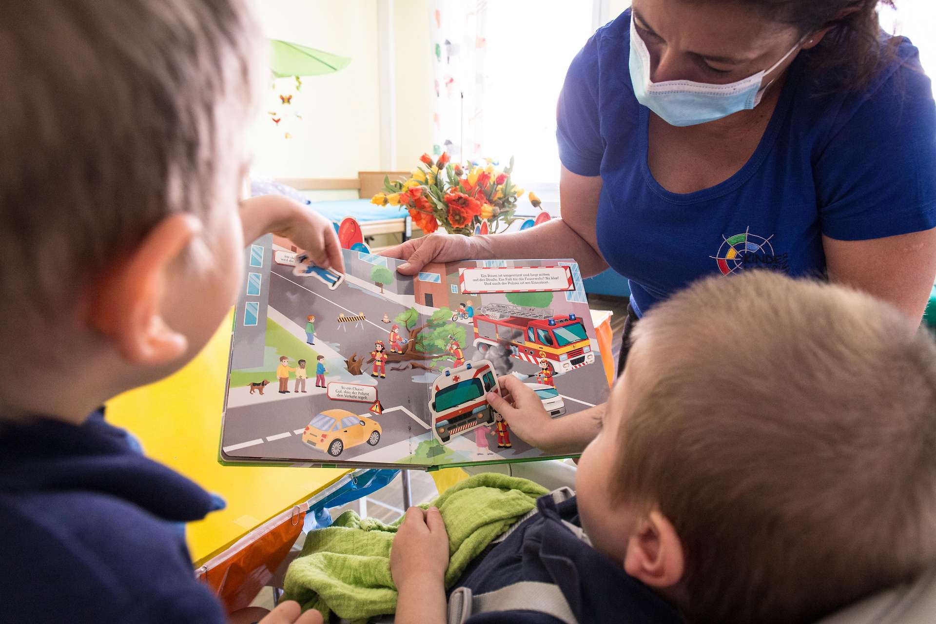 Kinderkrankenschwester mit Mundschutz betreut Kinder im Tageshospiz.