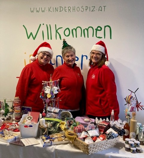 Drei Mitarbeiterinnen präsentieren das Angebot des Weihnachtsmarkts.
