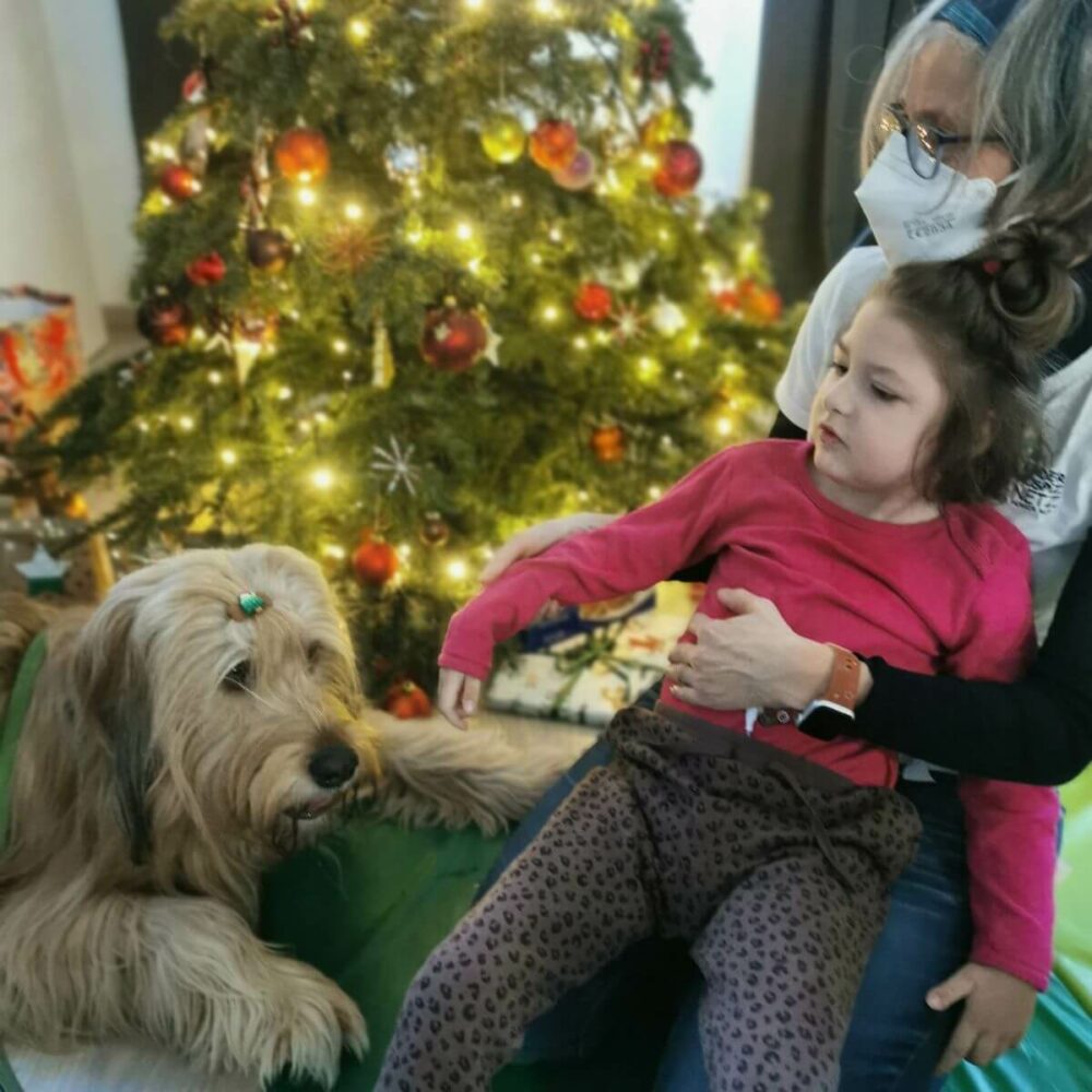 Hannah mit Hund Kind mit Betreuerin und Therapiehund vor dem Weihnachtsbaum