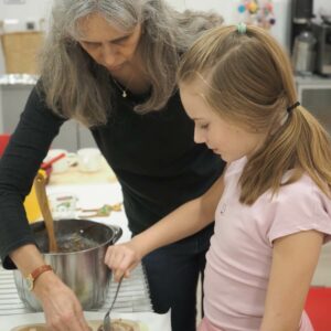 Die Pädagogin stellt mit einem Mädchen Futterringe für Vögel her.