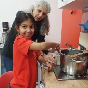 Ein Mädchen und die Pädagogin der Geschwistergruppe kochen gemeinsam.