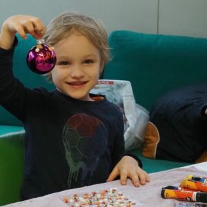 Ein Bub der Geschwistergruppe zeigt stolz eine Weihnachtskugel.