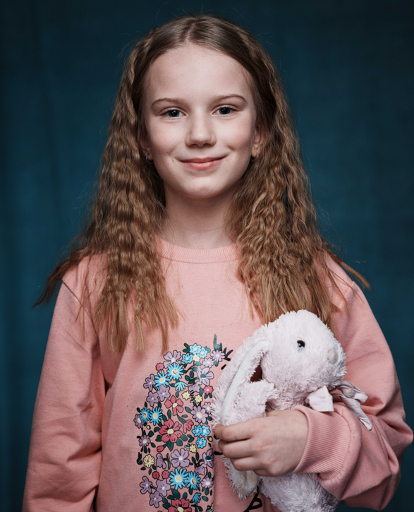 Ein Mädchen mit langen Haaren hält einen Stoffhasen im Arm.