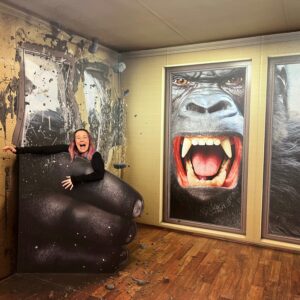 Frau wird durch ein Fenster hindurch von einem Riesengorilla angegriffen