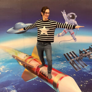 Frau steht auf einer Rakete, die durchs All fliegt