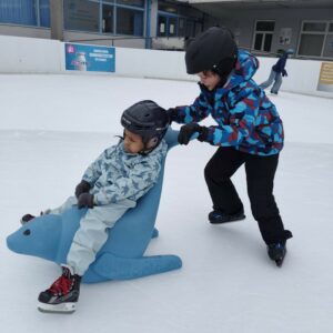 Ein Bub schiebt einen zweiten Buben über das Eis
