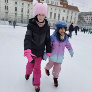 Zwei Mädchen fahren Hand in Hand übers Eis