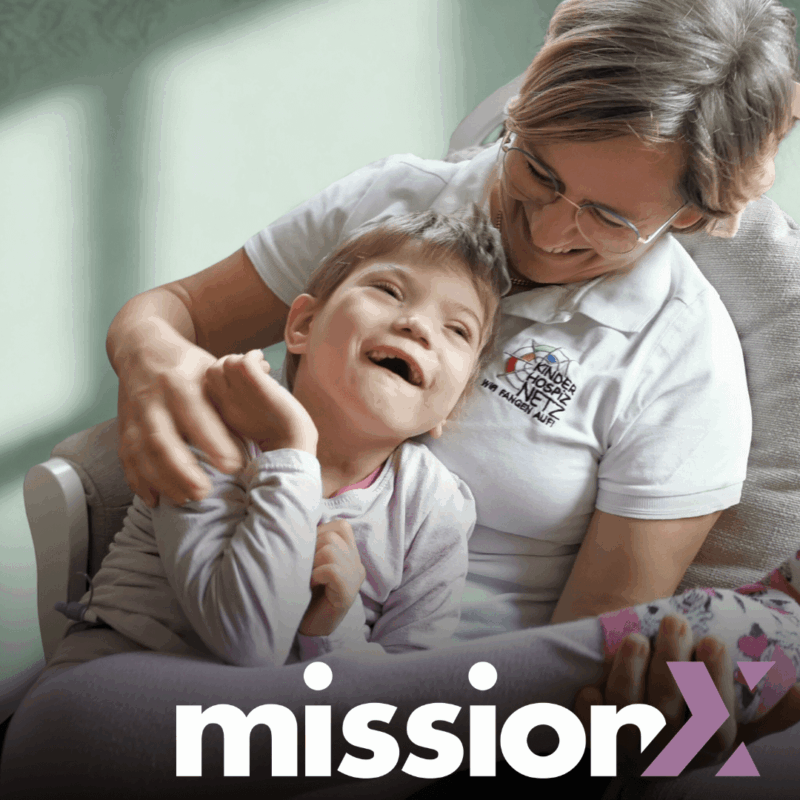 Pflegeperson hält ein lachendes Mädchen im Kindertageshospiz Netz