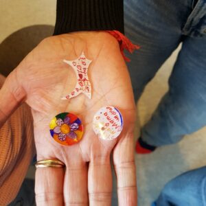 Drei bunt bemalte Glassplitter liegen auf einer Handfläche