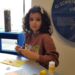 Ein Mädchen gestaltet eine bunte Karte